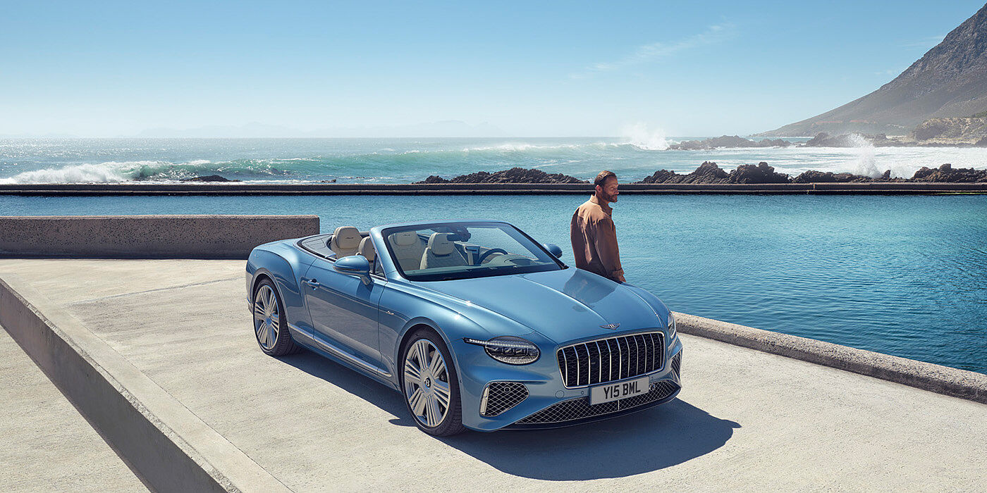 Bentley Casablanca New Bentley Continental GTC Azure convertible front view in Light Windsor blue paint with 22 inch ten spoke wheels parked by the sea in the sunshine