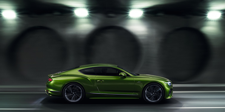 Bentley Casablanca Bentley Continental GT Speed coupe profile in Tourmaline Green driving dynamically past a concrete wall at night