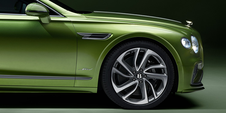 Bentley Casablanca Bentley Flying Spur Speed sedan exterior close up in Tourmaline Green paint with chrome B wing vent, chrome Speed badge and 22 inch ten swept spoke wheel