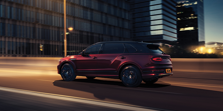 Bentley Casablanca Bentley Bentayga Extended Wheelbase Mulliner SUV in Cricket Ball red paint driving dynamically in city at night