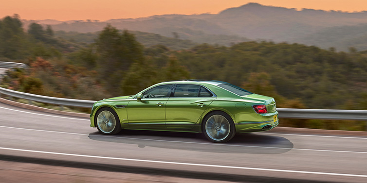 Bentley Casablanca Bentley Flying Spur Speed sedan side profile in Tourmaline Green paint driving dynamically on a mountain road at sunset