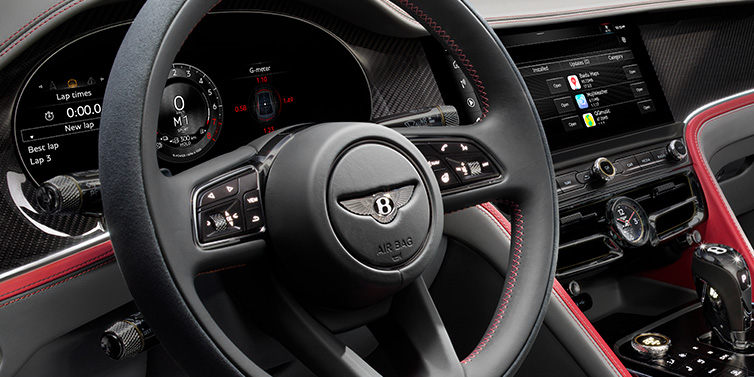 Bentley Casablanca Bentley Flying Spur Speed sedan front interior detail showing steering wheel and driver screens surrounded with Hotspur red and Gravity Grey hides